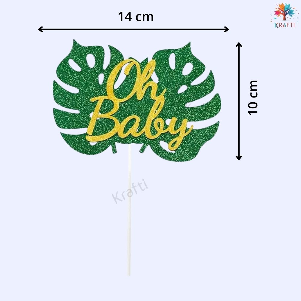 Oh Baby cake topper size guide showing green glitter monstera leaf and gold glitter lettering, approx 14 cm wide and 10 cm tall